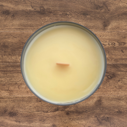 top-down view of a hand-poured beeswax candle with a natural golden surface and a centered wooden wick. Set in a clear glass container. Simple, traditional presentation with a raw, handmade look.